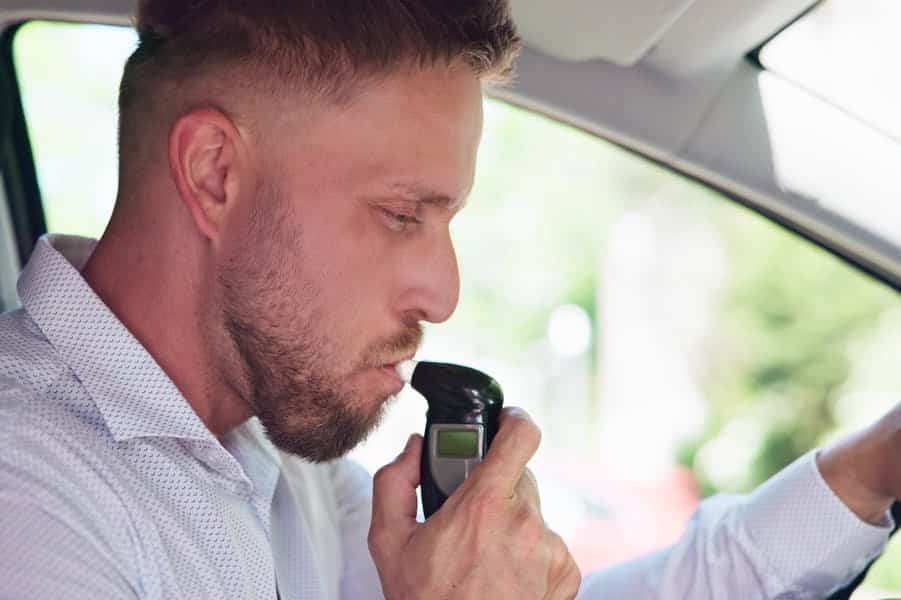 man blaast in een alcoholtester