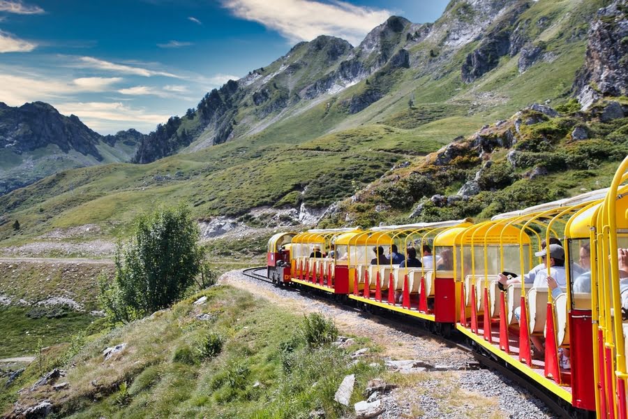 geel treintje rijdt door een berglandschap