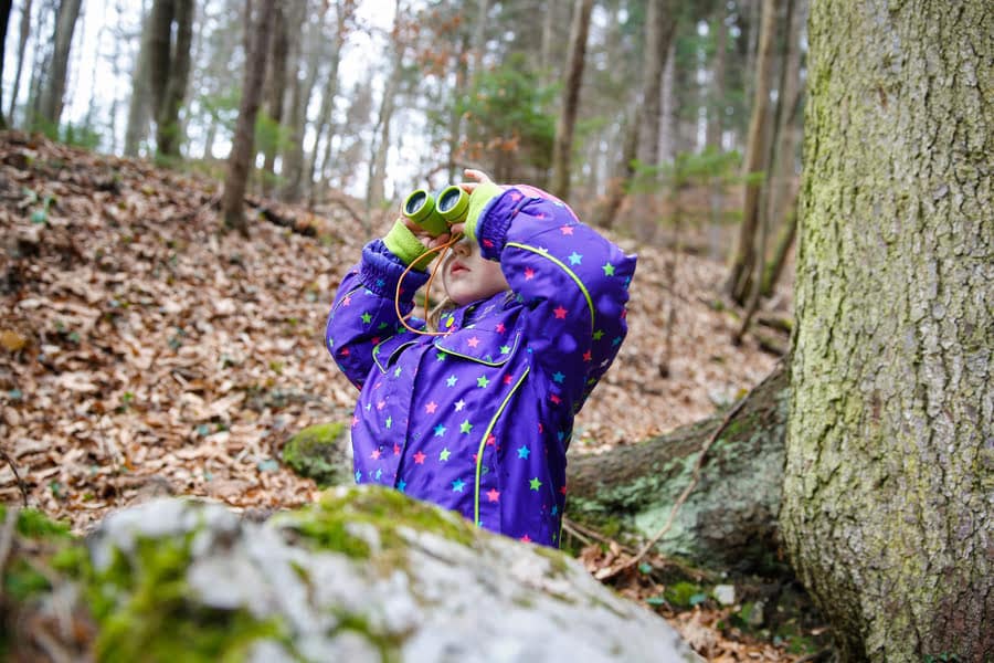 Kind met verrekijker in het bos